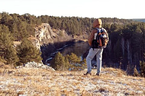 Back view of young man with backpack standing on mountain and looking view Stock Photos