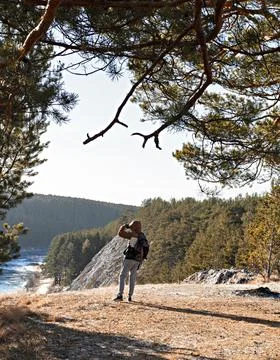 Back view of young man with backpack standing on mountain and looking at view Stock Photos