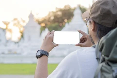 Back view of young man with backpack holding mobile phone with isolate screen Stock Photos