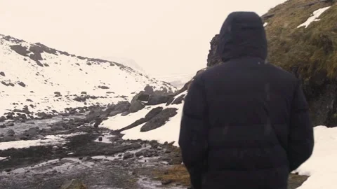Back view of young man in black jacket walking in winter mountain. Stock Footage 135420955