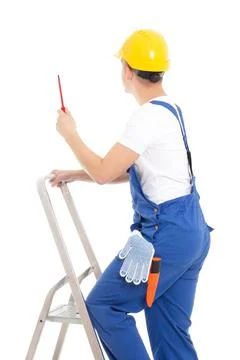Back view of young man builder in blue coveralls with screwdriver on ladder i Stockfoto's