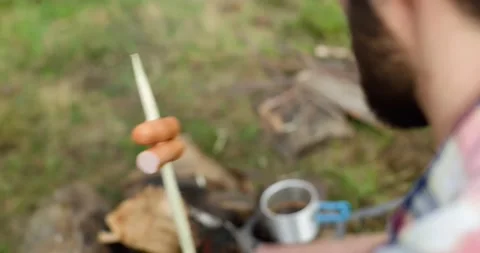 Back view of young man camping, preparing food on bonfire. Coffee on fire to Vídeo Stock 141747280