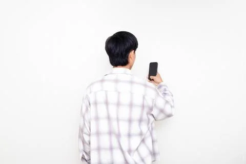 Back view of a young man holding a smartphone against a clean white backgroun Stock Photos