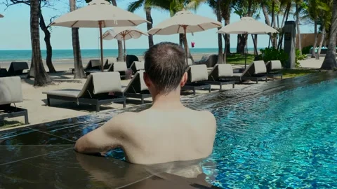 Back view of young man record video on smartphone while stand in swimming pool Stock Footage 201062391