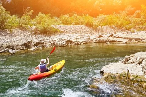 Back view of young man in red-yellow plastic boat in canyon of  mountain river Stock Photos