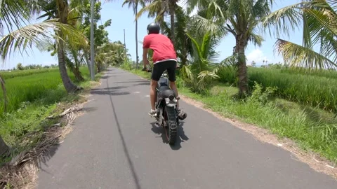 Back view young man riding on a black custom bike among of the road surrounded b Stock Footage 131804249