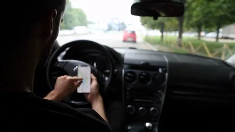 Back View of Young Man Using Phone Inside Car on Driver Seat. Stockbeeldmateriaal 109604731