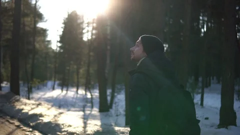 Back view of young man walking in winterwood with backpack. Stock Footage 93324473