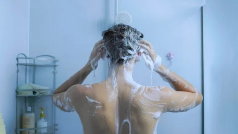 Back view of a young man washing his hair and skin under the shower. Stock Footage 345531195