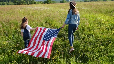 Back view of young mother and little daughter kid running with American flag Stock Footage 155828620