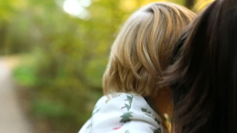 Back view of young mother walking across forest holding little blonde child by Vidéo 125191326