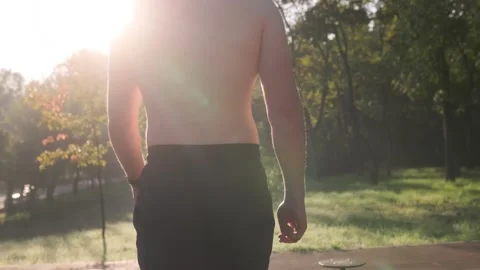 Back view of A Young Muscular Man with Naked Torso Walking Outside, Focused on Vídeos de archivo 331252399