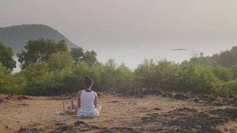 Back view of young painter sitting outdoors in mountains painting marine Stock Footage 132475242