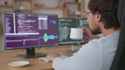 Back view of young programmer is working on computer sitting in the office Stock Footage 151328408