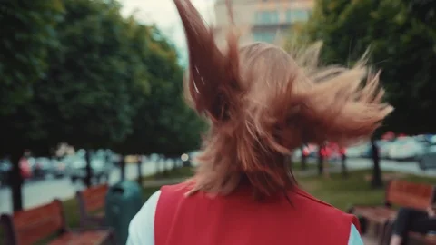 Back view of young short-haired woman acting happily while walking down the Stock Footage 91450416