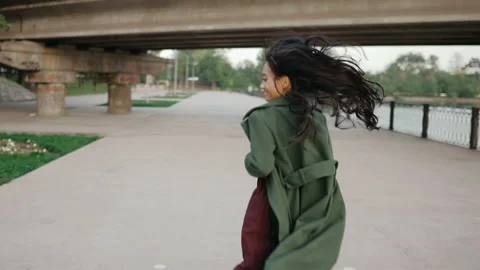 Back view of young smiling asian woman running turning around and looking to Stock Footage 143713115