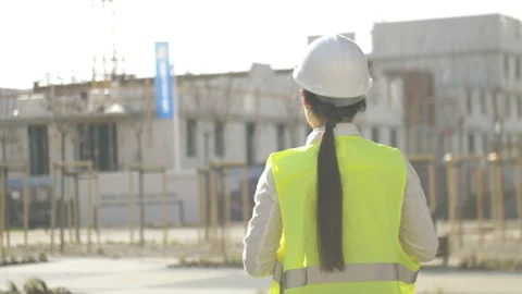 Back view of a young woman builder who stands on the construction site and Stock Footage 127501902