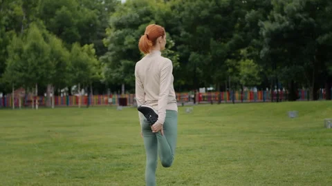 Back view of young woman do legs stretch after outdoor exercise. Stock Footage 295779659