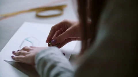 Back view of young woman erasing on paper with sketch of blue shoes. Designer Stock Footage 72682704
