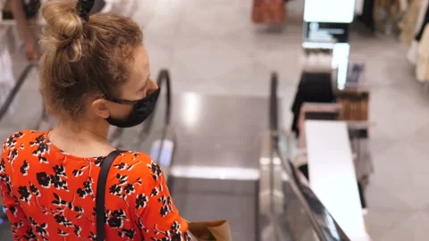 Back view of young woman in face mask going down on an escalator in shopping Vídeo Stock 138139877