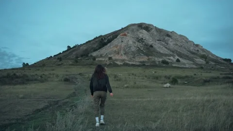 Back view of a young woman in a jacket climbing a high mountain Vidéo 144980155