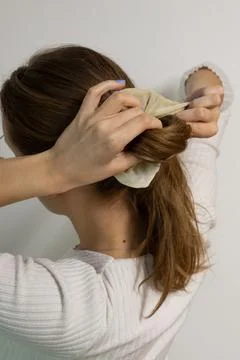 Back view of a young woman in a process of making her ponytail Foto stock