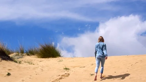 Back view of young woman running up on sand hills and greeting somebody. Stock Footage 112657475