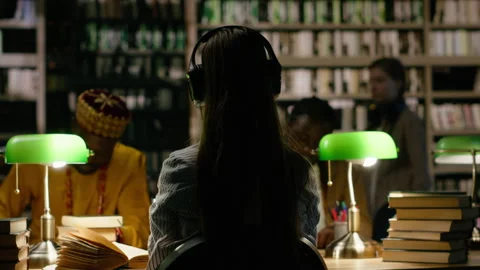 Back view of young woman seated with classmates in dark library study room Stock Footage 337232804
