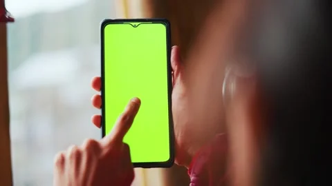 Back view of young woman using green screen smart phone at home. Woman doing a t Stock Footage 323187126