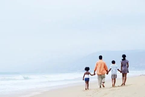 Back, walking and holding hands with black family at beach for bonding, support Stock Photos