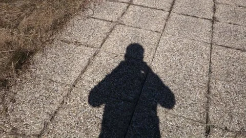 Back walking man's shadow on stone pavement Stock Footage 172383947