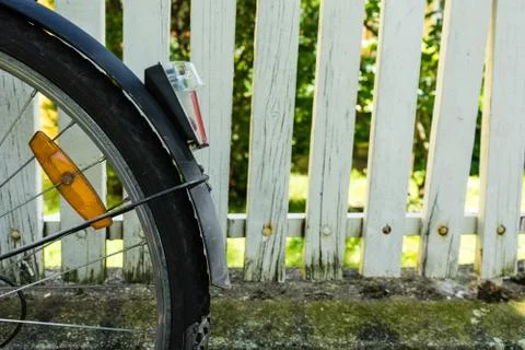 Back wheel of bicycle in front of white fence Stock Photos