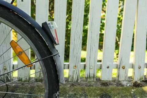 Back wheel of bicycle in front of white fence Stock Photos