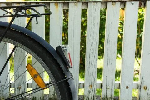 Back wheel of bicycle in front of white fence Stock Photos