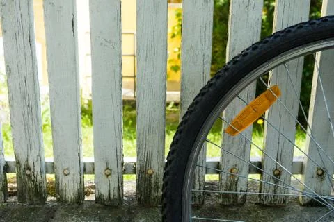 Back wheel of bicycle in front of white fence Foto stock