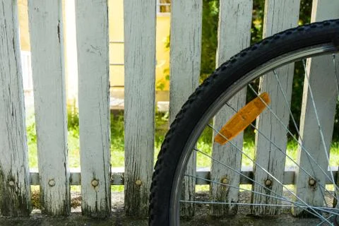 Back wheel of bicycle in front of white fence Stock Photos