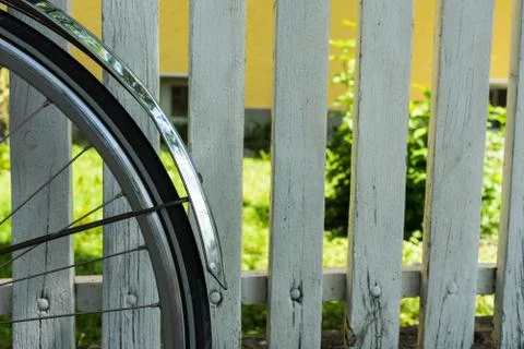 Back wheel of bicycle in front of white fence Stock Photos