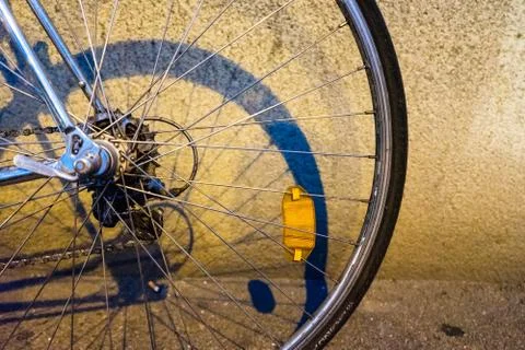 Back wheel of a bicycle in the night in front of a wall Stock Photos