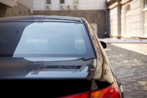 Back window of black car parked on the street in summer sunny day, rear view. Stock Photos