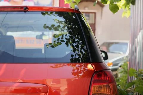 Back window of red car parked on the street in summer sunny day, rear view. M Stock Photos