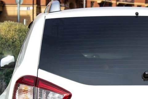 Back window of a white car parked on the street near houses, rear view. Mock-up Stock Photos
