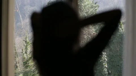 Back of woman looking to big window and and playing with her hair Stock Footage 46686796
