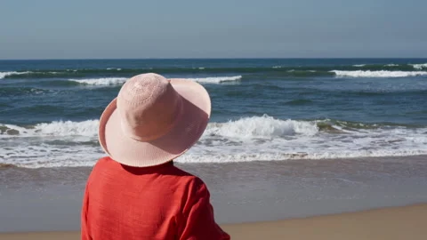 From the back of a woman looking at the waves breaking on the beach Stock Footage 242671886