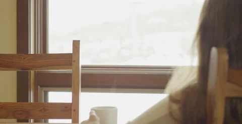 Back of woman's head holding steaming mug looking out snowy window Stock Footage 203975647