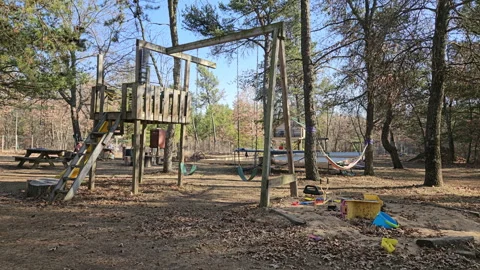 Back yard with set of empty swing set next to sandbox and slide Stock Footage 268916605