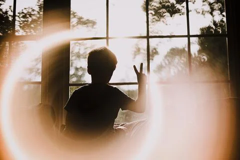 Back of Young Boy in Window Making Peace Sign With Circle Light Effect Stock Photos