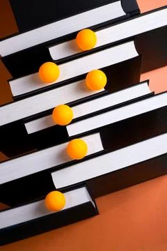 A backdrop of stacked books on a colored background with colorful balls. Stock Photos