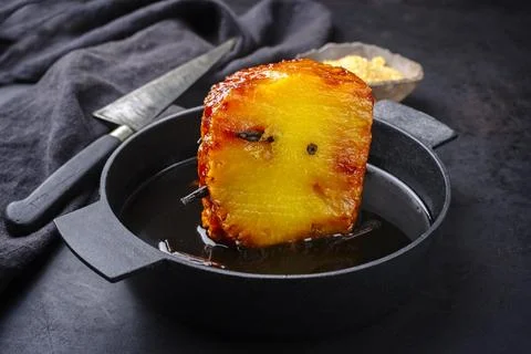 Backed caramelized pineapple with vanilla caramel sauce as top view on a mode Stock Photos