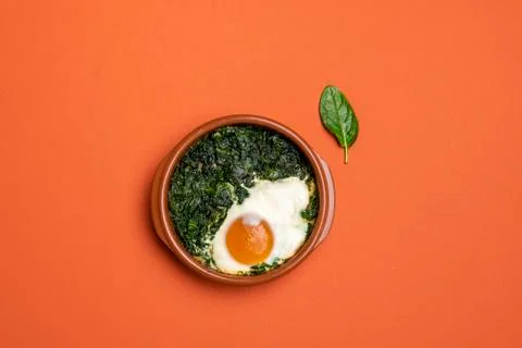 Backed egg and spinach in a small clay pot Stock Photos