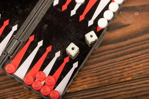 Backgammon board with chips and dice on a wooden table, close-up, selective f Stock Photos